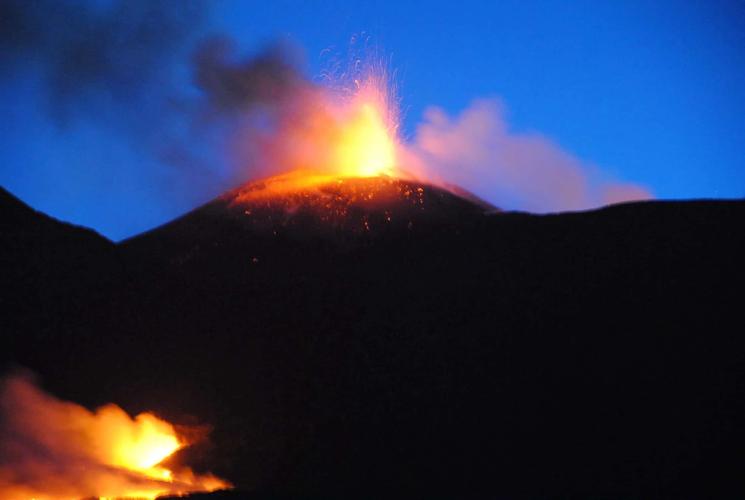 L'Etna in eruzione nella notte: fontana di lava dal cratere e colata incandescente