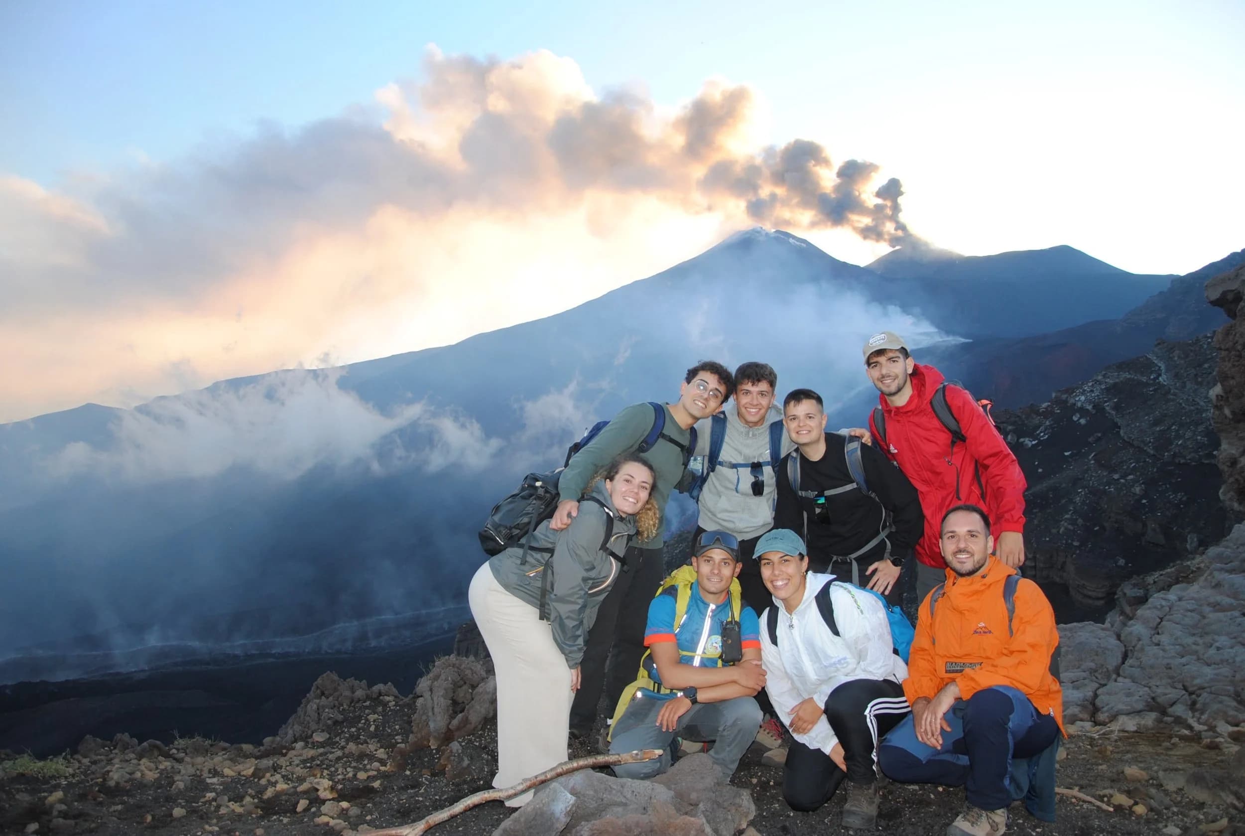 Il gruppo di escursionisti al tramonto davanti all'eruzione: la scala umana sul vulcano