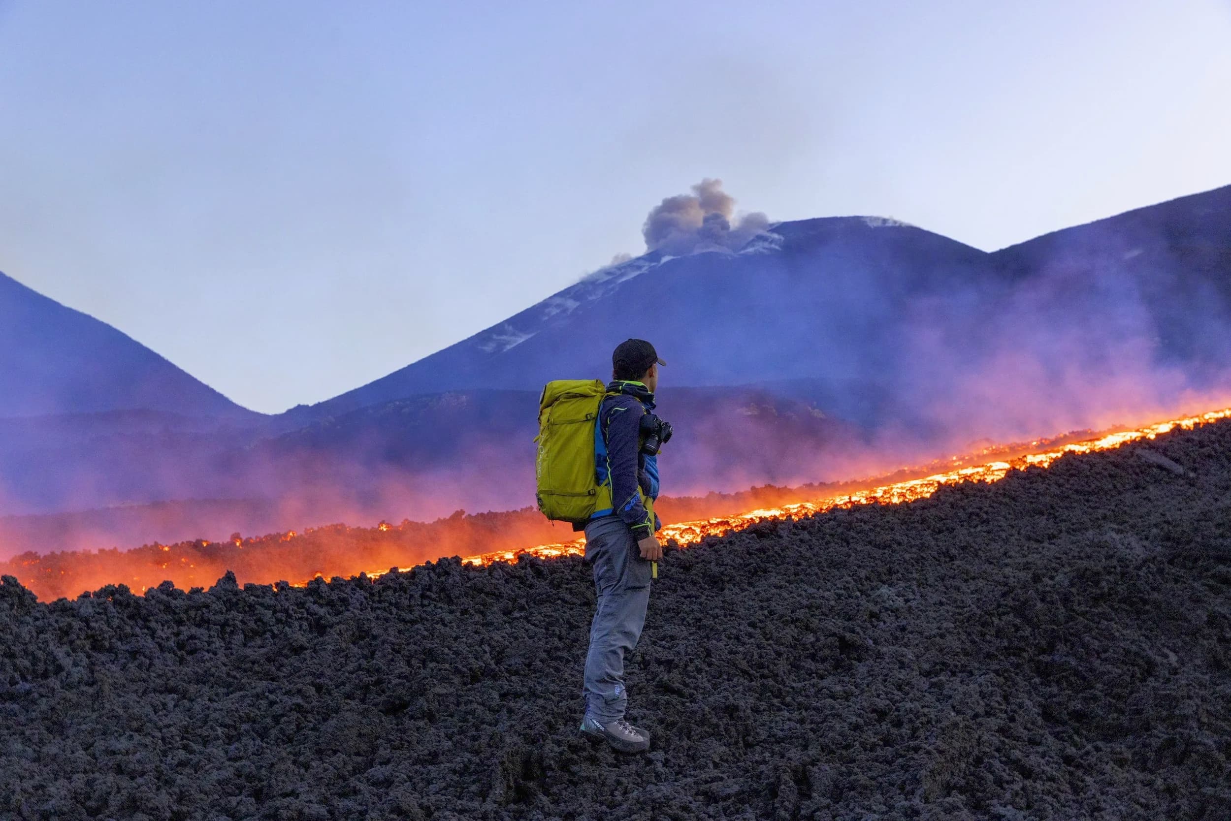 Un escursionista solo sul campo lavico al crepuscolo, nel deserto di cenere